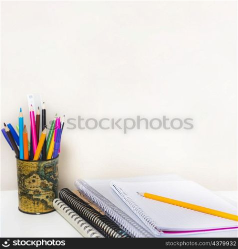 notebooks near cup with pencils