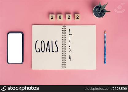 Notebooks with empty goals for 2022 year and phone on color background