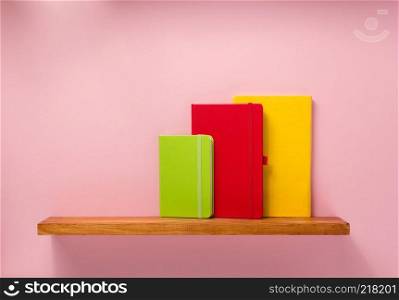 notepad and book on shelf at wall background surface