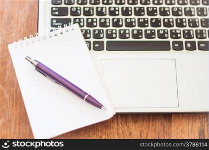 Notepad and laptop on wooden table, stock photo