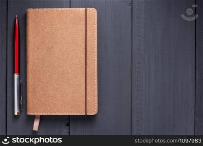 notepad and pen at black wooden background surface table, top view