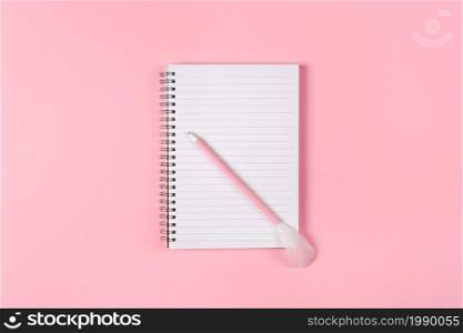 Notepad and pink pen decorated with feather on pink background. Woman power concept.. Notepad and pink pen decorated with feather on pink background. Woman power concept