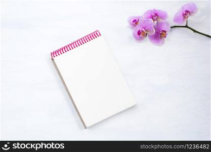 Notepad mockup with pink orchid on the white table