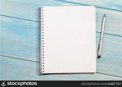 notepad on table. blank page of chequered notepad with pen on blue wooden table