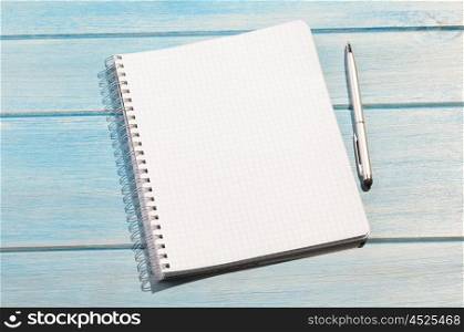 notepad on table. blank page of chequered notepad with pen on blue wooden table