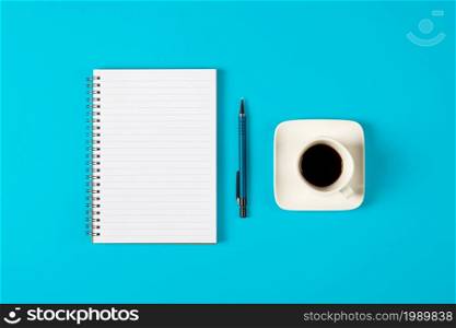 Notepad, pen and a cup of coffee isolated on light blue background. Notepad with copy space. Office, business, discreet style.. Notepad, pen and a cup of coffee isolated on light blue background. Notepad with copy space. Office, business, discreet style
