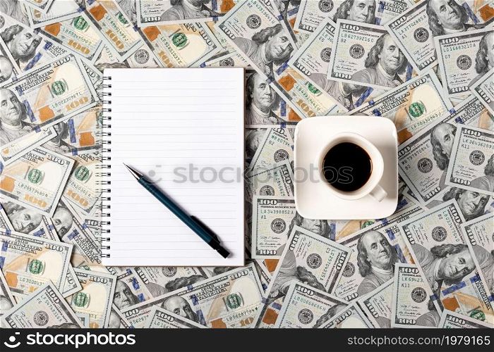Notepad, pen and a cup of coffee isolated on money background. Notepad with copy space. Office, business, discreet style.. Notepad, pen and a cup of coffee isolated on money background. Notepad with copy space. Office, business, discreet style