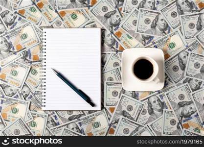Notepad, pen and a cup of coffee isolated on money background. Notepad with copy space. Office, business, discreet style.. Notepad, pen and a cup of coffee isolated on money background. Notepad with copy space. Office, business, discreet style
