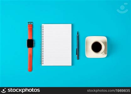Notepad, watch, pen and a cup of coffee isolated on blue background. Notepad with copy space. Office, business, discreet style.. Notepad, watch, pen and a cup of coffee isolated on blue background. Notepad with copy space. Office, business, discreet style