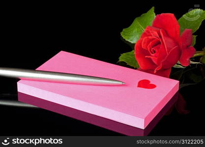 notepad with a heart , pen and rose reflected in black