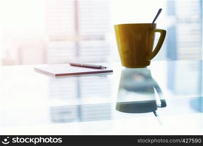 Notepad with pen and coffee cup on table in office with outside view of blurred business center building.