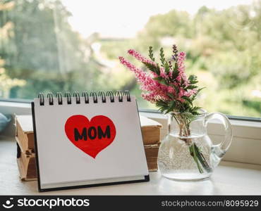 Notepad with the word MOM. Closeup, indoors. Congratulations for family, loved ones, friends and colleagues. Notepad with the word MOM. Closeup, indoors