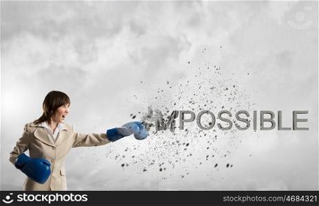 Nothing is impossible for her. Young businesswoman in blue boxing gloves breaking impossible word