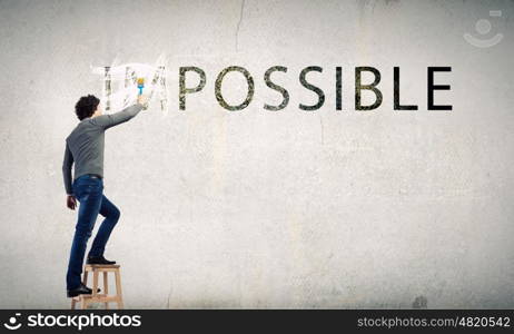 Nothing is impossible. Man changing word impossible in to possible by erasing part of word with paint brush