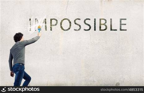 Nothing is impossible. Man changing word impossible in to possible by erasing part of word with paint brush