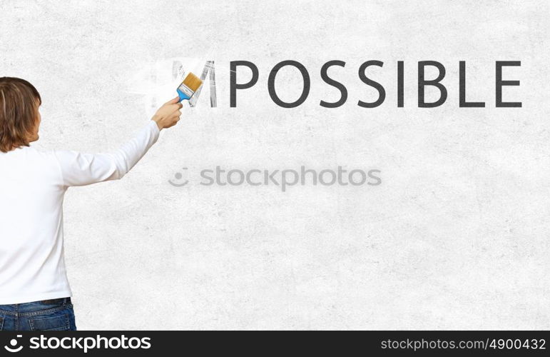 Nothing is impossible. Man changing word impossible in to possible by erasing part of word with paint brush