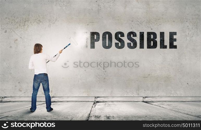 Nothing is impossible. Man changing word impossible in to possible by erasing part of word with paint roller