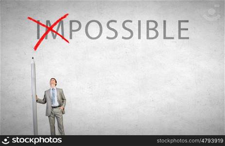Nothing is impossible. Young businessman with huge pencil changing word impossible