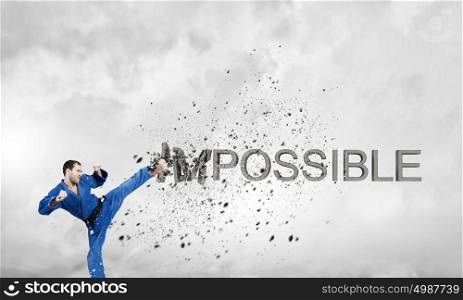 Nothing is impossible. Young determined karate man breaking stone impossible word