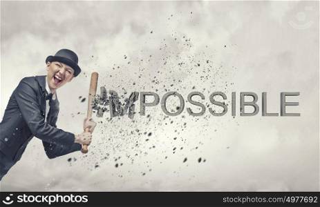 Nothing is impossible. Young emotional woman crashing word impossible with baseball bat