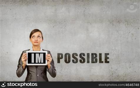 Nothing is impossible. Young woman holding tablet pc with word