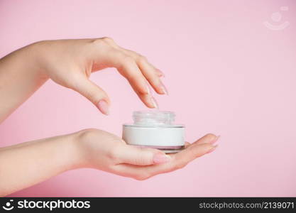 Nourishing cream and beautiful female hands on a pink background. Skin care concept. Image for advertising and design.. Nourishing cream and beautiful female hands on pink background. Skin care concept. Image for advertising and design.