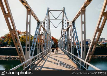 NOV 18, 2014 Okayama, Japan - Local Japanese tourists walking on old Iron bridge crossing Asahi river at Okayama castle