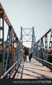 NOV 18, 2014 Okayama, Japan - Local Japanese tourists walking on old Iron bridge crossing Asahi river at Okayama castle