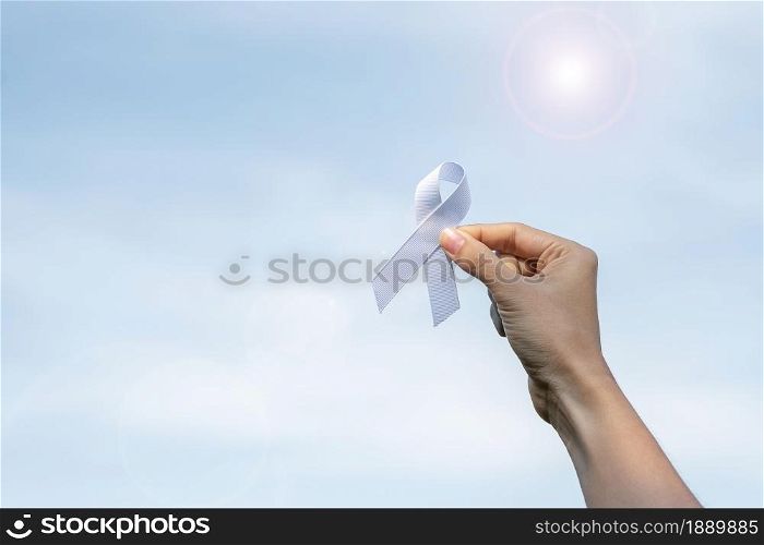 November Lung Cancer Awareness month, democracy and international peace day. Woman holding white Ribbon on sky background