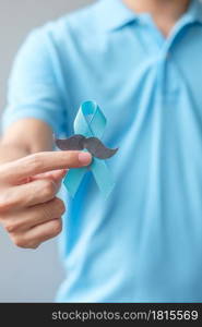 November Prostate Cancer Awareness month, Man holding Blue Ribbon with mustache for supporting people living and illness. Healthcare, International men, Father and World cancer day concept