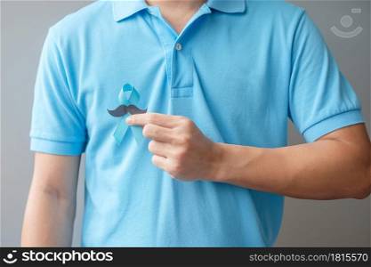 November Prostate Cancer Awareness month, Man holding Blue Ribbon with mustache for supporting people living and illness. Healthcare, International men, Father and World cancer day concept