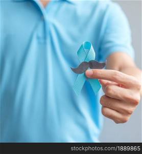 November Prostate Cancer Awareness month, Man holding Blue Ribbon with mustache for supporting people living and illness. Healthcare, International men, Father and World cancer day concept