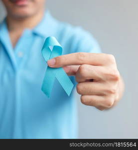 November Prostate Cancer Awareness month, Man in blue shirt with hand holding Blue Ribbon for supporting people living and illness. Healthcare, International men, Father and World cancer day concept