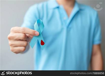 November World Diabetes day Awareness month, man holding light Blue Ribbon with blood drop shape for supporting people living, prevention and illness. Healthcare, prostate cancer day concept