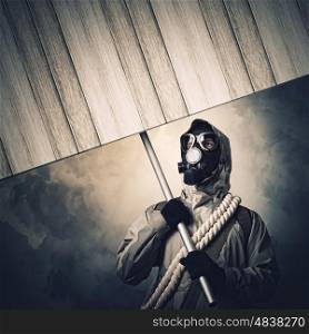 Nuclear future. Stalker in gas mask with wooden banner. Disaster concept