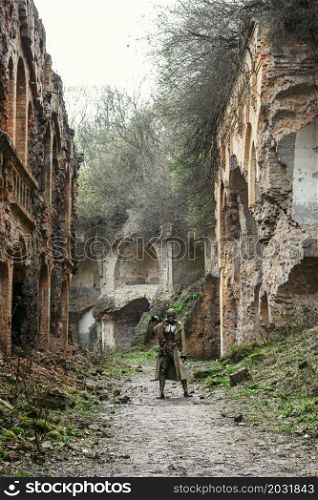 Nuclear post-apocalypse. Sole survivor in tatters and gas mask on the ruins of the destroyed city. Nuclear post-apocalypse survivor