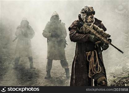 Nuclear post-apocalypse. Survivors in tatters and gas mask on the ruins of the destroyed city. Nuclear post-apocalypse survivors
