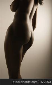 Nude African American mid adult female with back to viewer showing breast and hips.