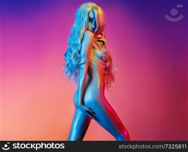 Nude beautiful blonde dancing in colorful light. Erotic portrait of sexy woman with long hairs. Sexual naked model pose on pink background. Perfect female body of elegant stripper. Pretty girl.