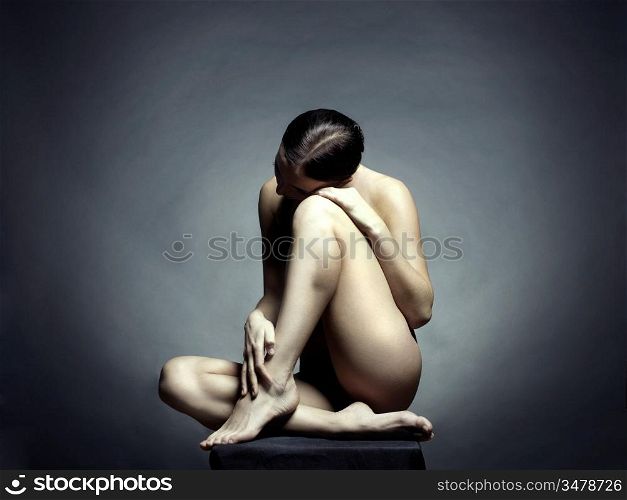 Nude beautiful sitting lady on black background