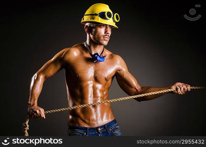 Nude builder pulling rope in darkness