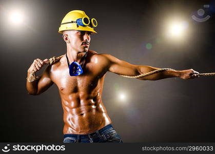 Nude builder pulling rope in darkness