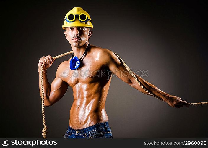 Nude builder pulling rope in darkness
