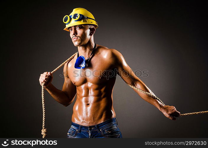 Nude builder pulling rope in darkness