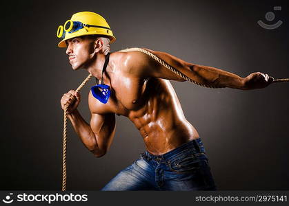 Nude builder pulling rope in darkness