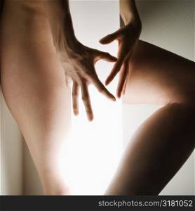 Nude Caucasian female body grasping light pole.