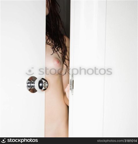 Nude Caucasian woman standing in partially opened door.