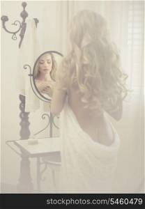 Nude elegant blonde woman in front of the mirror