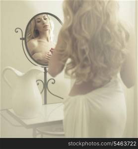 Nude elegant blonde woman in front of the mirror