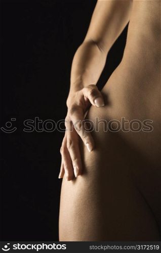 Nude Hispanic mid adult female hand on hip.